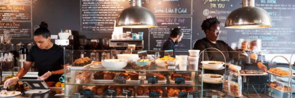 Staff Working Behind Counter In Busy Coffee Shop